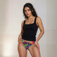 Woman wearing a black tank top and colorful patterned underwear against a plain background